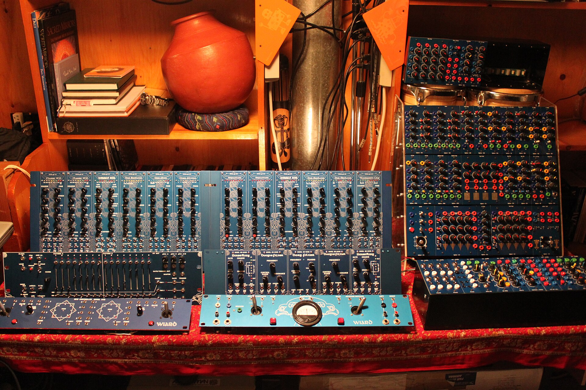 A wall of modular synthesizer units with patch cables in a studio.